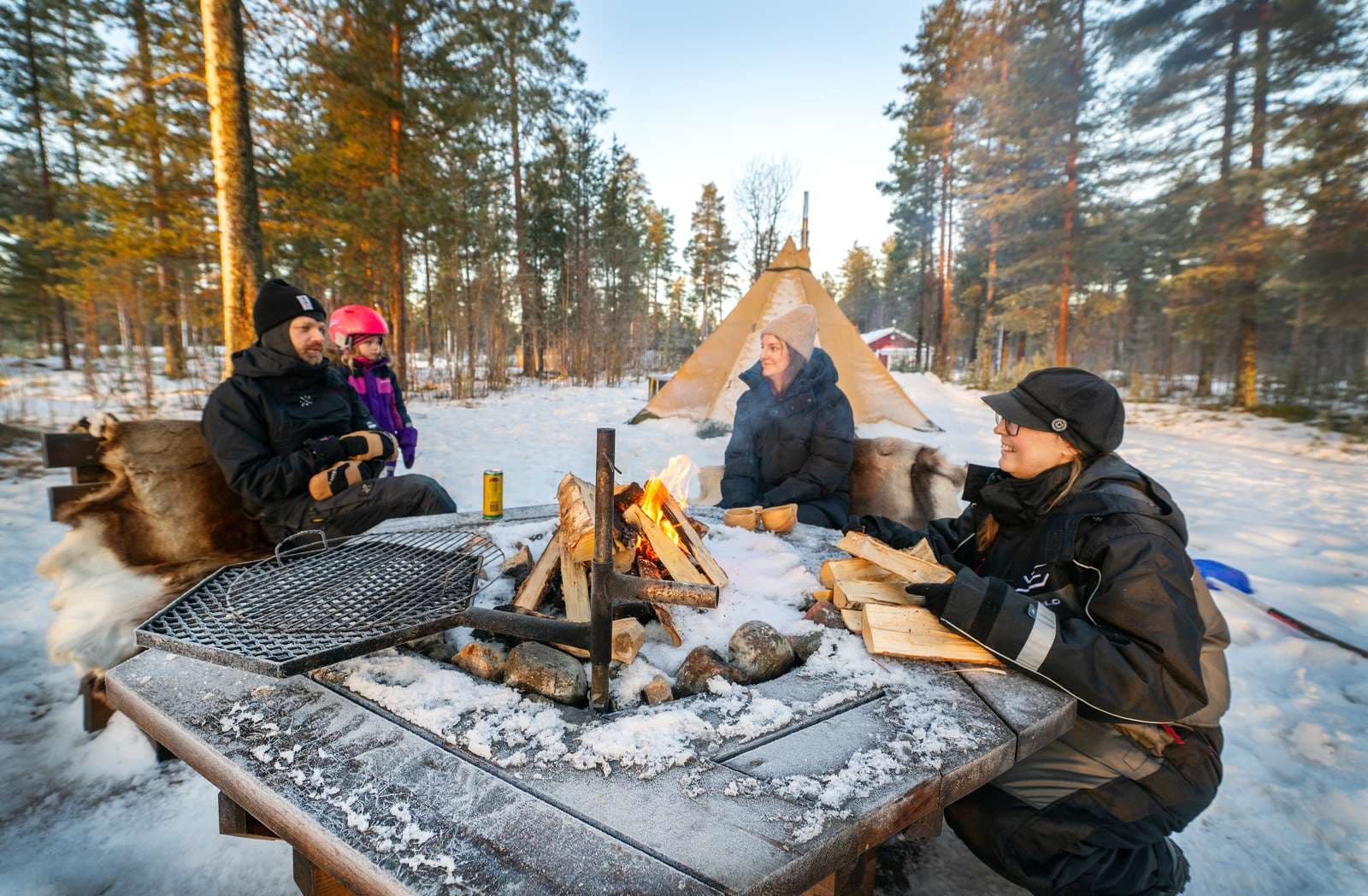 Familj som sitter och grillar i vinternaturen i luleå