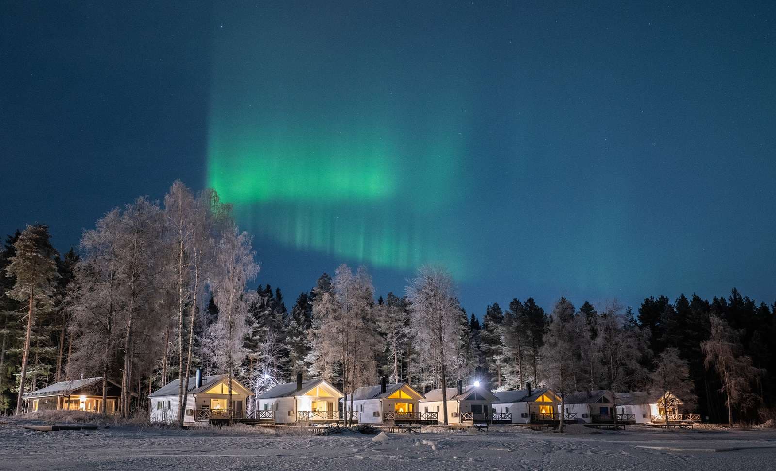 Arcus Luleå campingvy med norrsken över området och stugor
