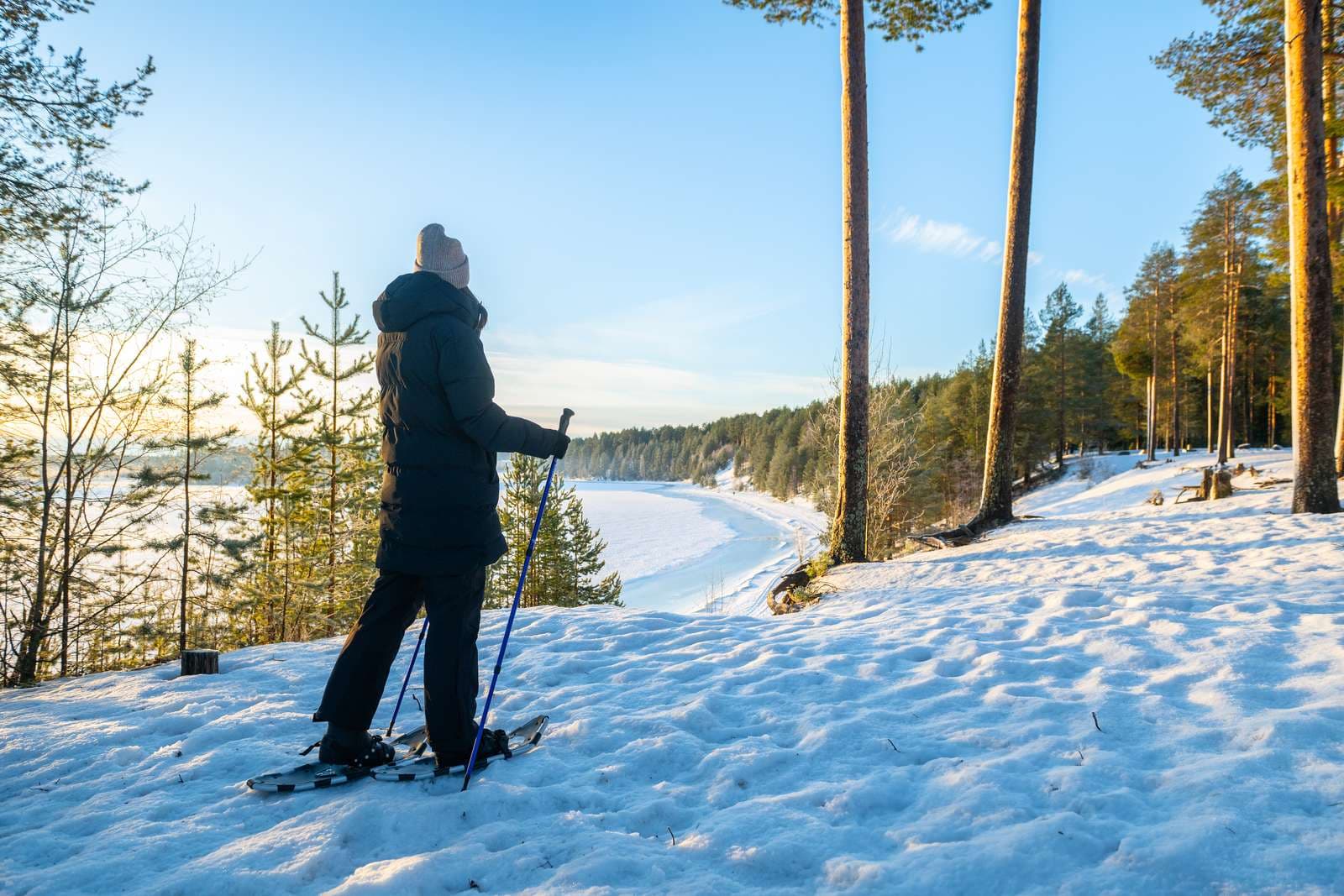 Person som går med snöskor i skogen under vintern. Vacker vy över isen och naturen.