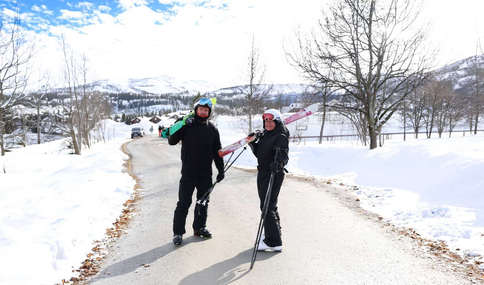 Två personer som håller i skidor och snowboard. Påväg till backarna från campingområdet med massa snö runt omkring.
