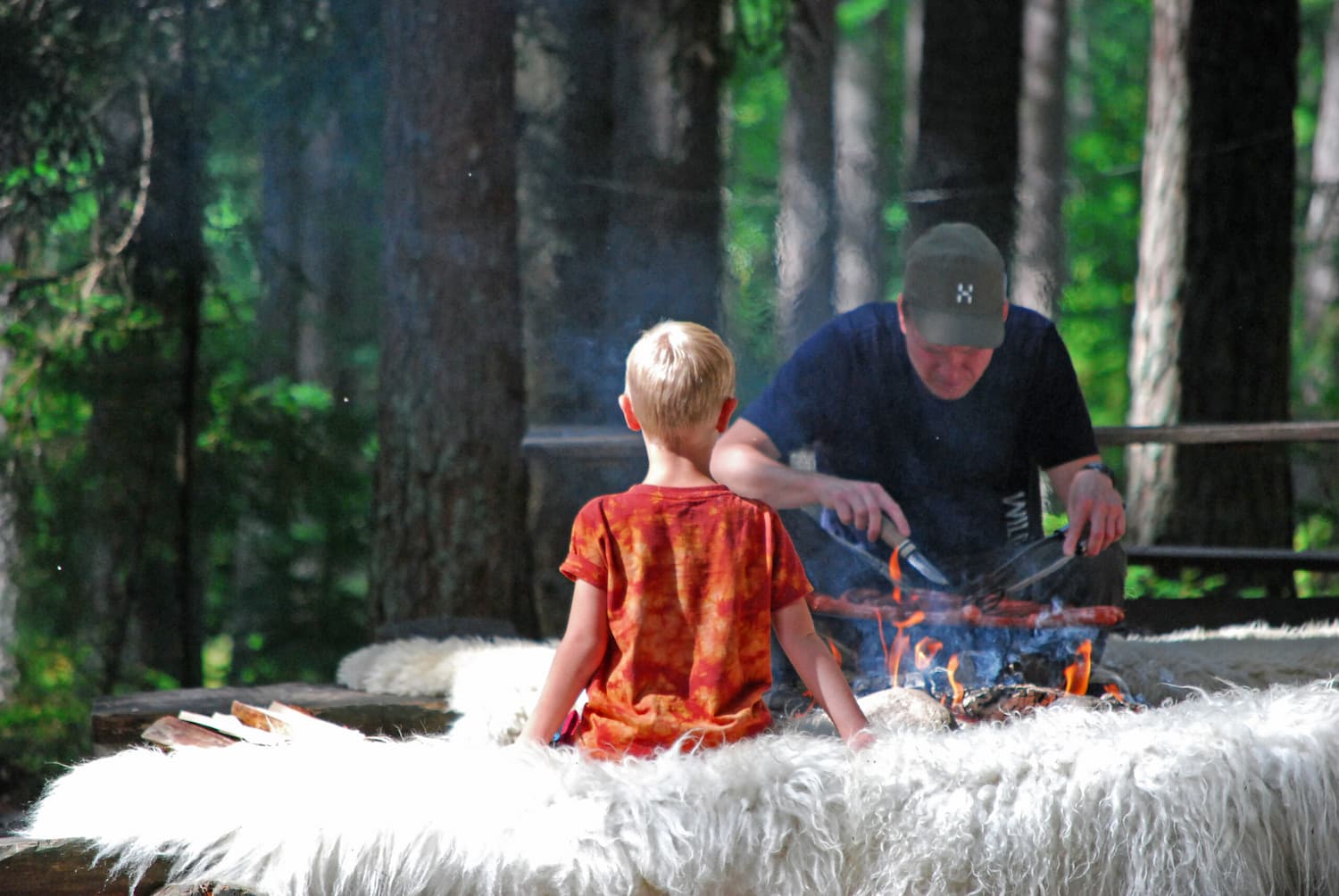 En pappa och en son som grillar i skogen.