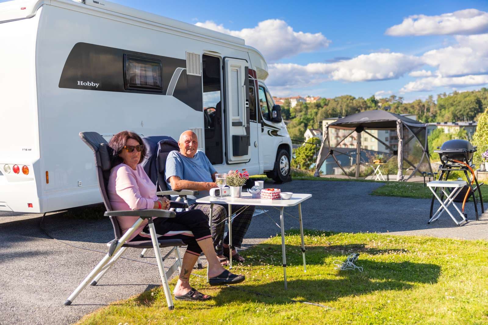 Ett par som sitter vid ett bord framför husbilen på campingen City Strömstad