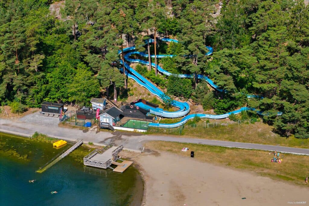 Drönarbild över stranden, naturen och den långa vattenruschbanan på Nickstabadet