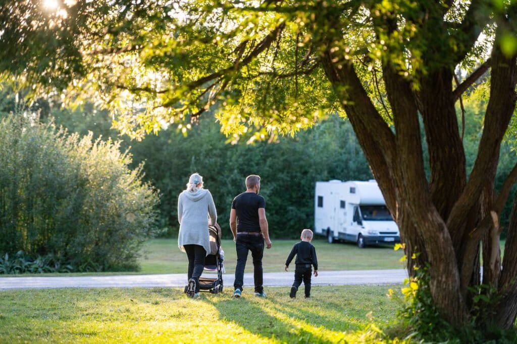 Familj som går mot husvagnen i vcacker natur på Nydala Umeå