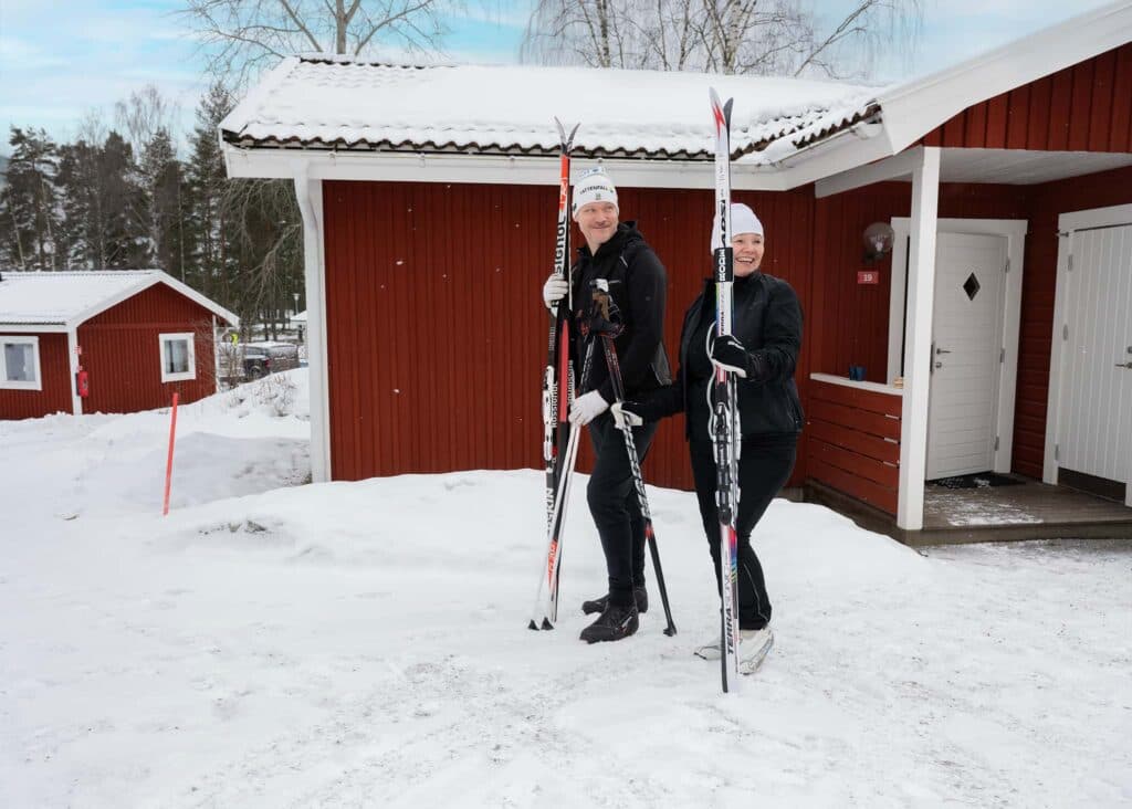 Familj med längdskidor utanför sin stuga på First Camp Lugnet Falun