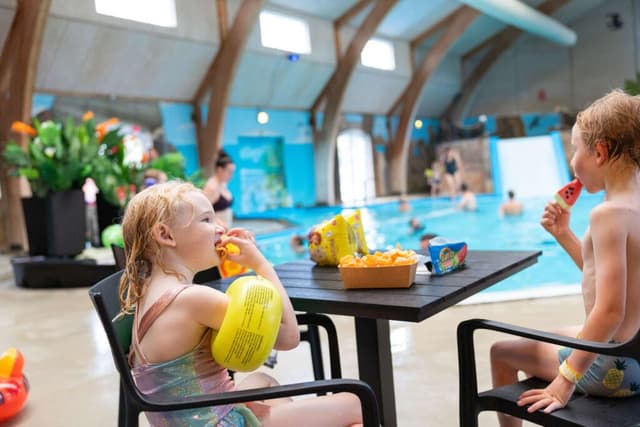 1. Familj som fikar tillsammans vid inomhusbadlandet på First Camp Hasmark Strand