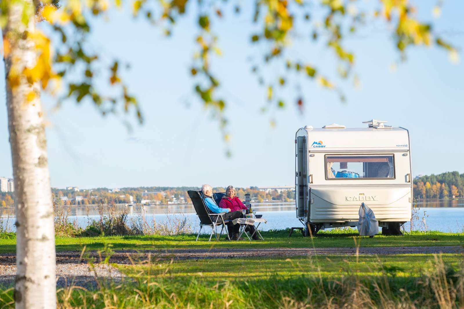 Par som sitter utanför husvagnen med usikt över Luleälven