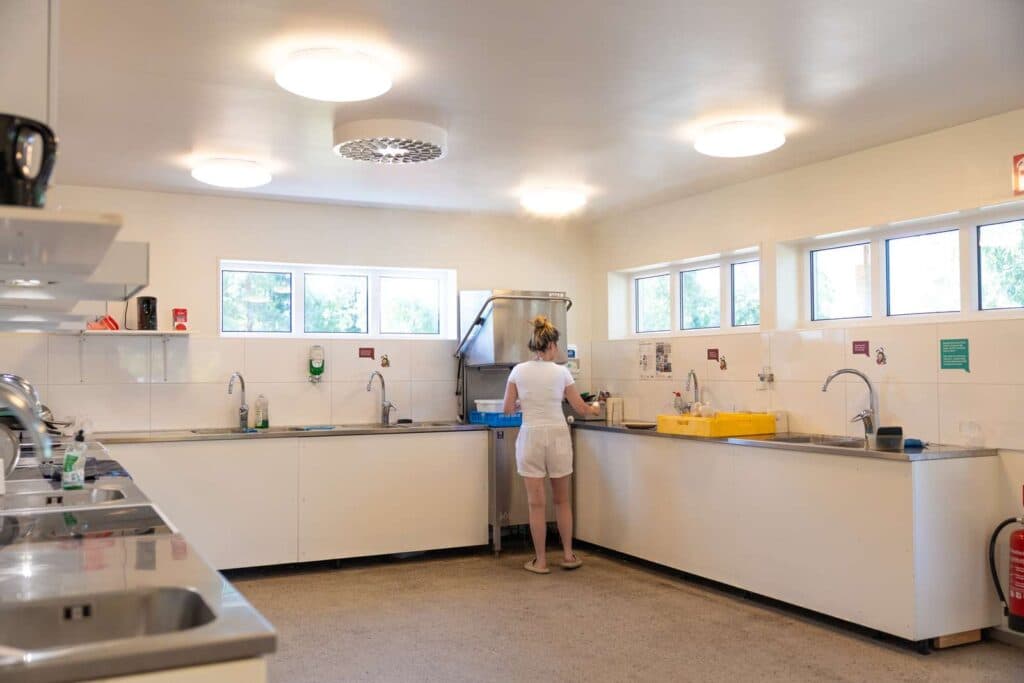 Person som står och diskar inne i ett servicehus på Skara Sommarland camping