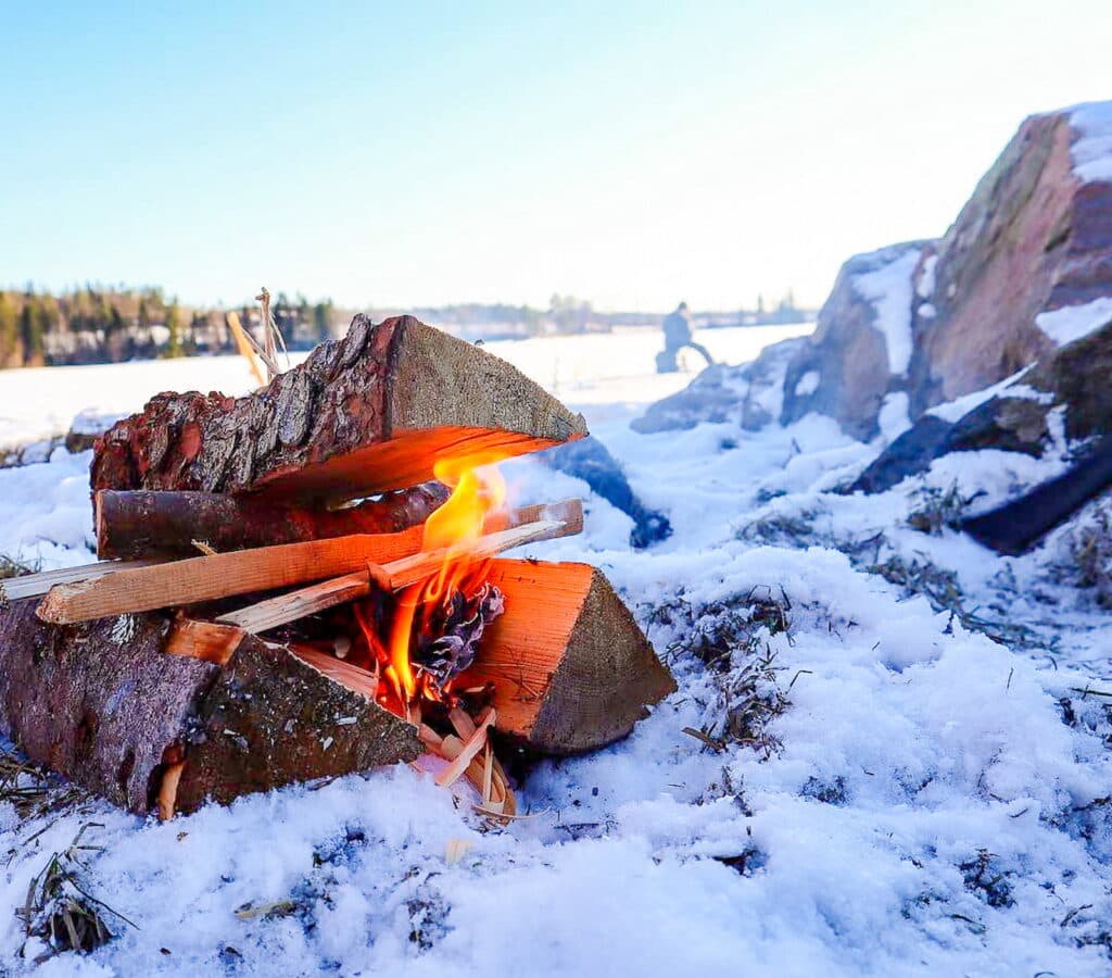 Vintercamping i Årjäng där familjen samlas kring elden för att grilla korv.