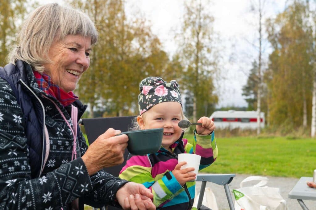 Barn och vuxen som sitter ute i höstnaturen och dricker gott
