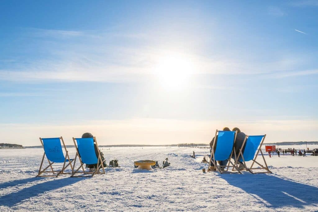 Vinyetrbild från isen och människor som sitter i solstolar och tittar ut över isen och aktiviteter som skoter, skridskor m.m.